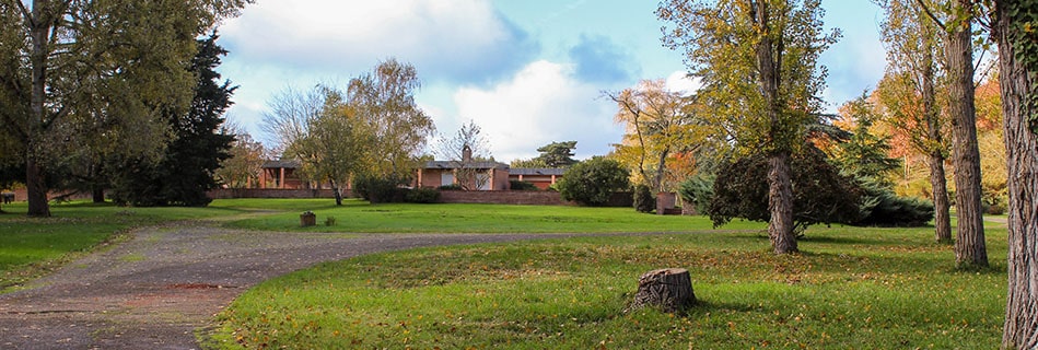 La villa Gélis de plain-pied, façade en briques et poteaux-poutres béton, au fond d'un vaste parc arboré aux couleurs d'automne