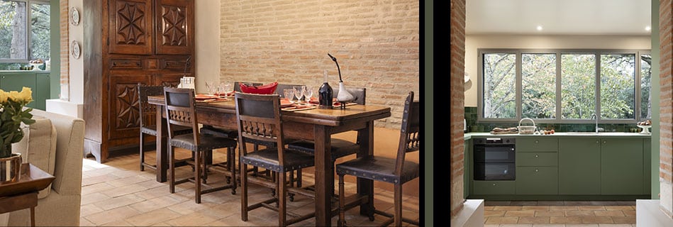 Salle à manger devant un mur de brique apparente et cuisine verte ouverte sur le parc par une fenêtre atelier