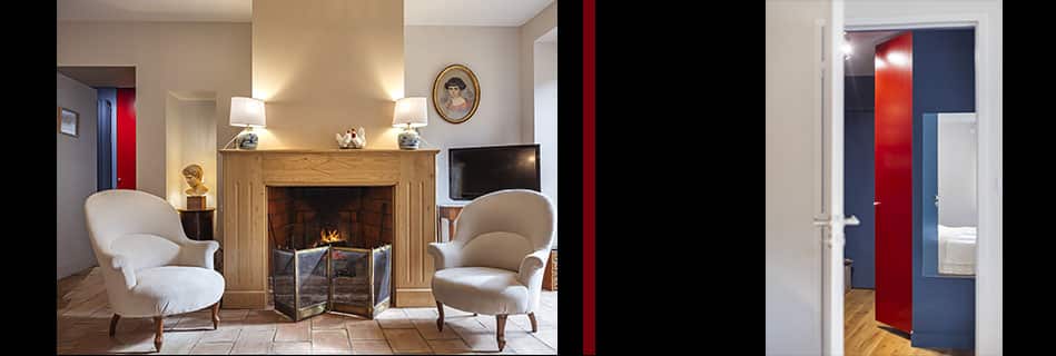 Coin salon autour d'une cheminée en pierre, fauteuils crème et circulation soulignée de rouge et de bleu