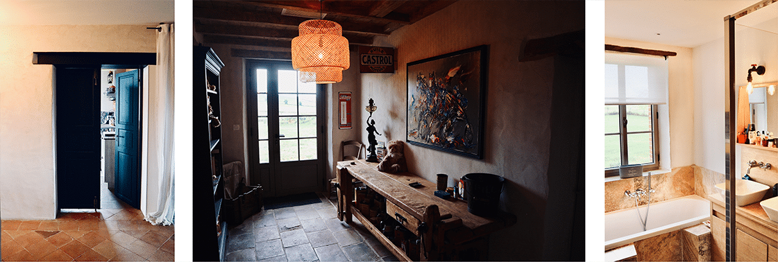 Entrée au sol de terre cuite et porte-fenêtre noire, banc ancien sous une suspension en osier, et salle de bain baignée de lumière
