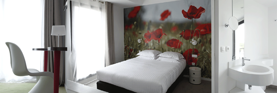 Chambre à la fresque de coquelicots en tête de lit, fauteuil design et salle d'eau à vasque ronde