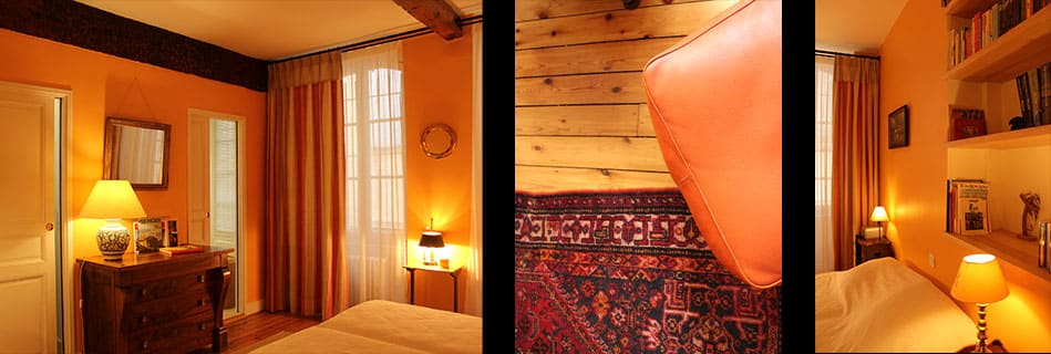 Chambre aux murs ocre : commode ancienne et miroir, tête de lit en cuir orange sur tapis persan, niches à livres et lampe de chevet