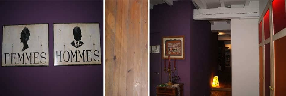 Détails d'intérieur : plaques émaillées Femmes et Hommes sur mur aubergine, parquet en bois brut et dégagement aux poutres peintes en blanc