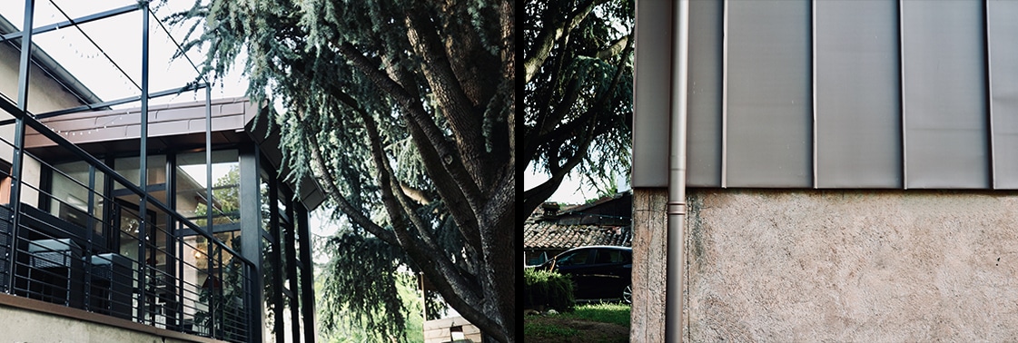 La boîte de verre en surplomb sur la terrasse près du cèdre, et détail du bardage en zinc pigmento de teinte rosée sur l'ossature bois