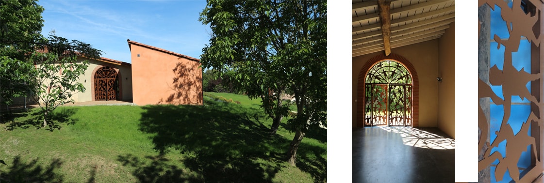 Volume enduit ocre du pôle jeunesse au milieu des arbres, et hall ouvert par une grande porte cintrée en acier corten découpé de silhouettes