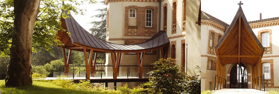 L'auvent d'accès en bois et zinc courbe près de la tour en brique, et son pignon à croix formant la nouvelle porte d'entrée